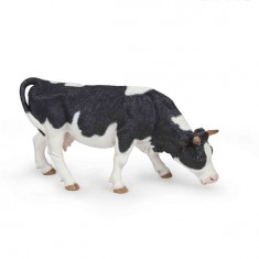 Black and white cow figurine grazing